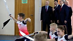Russian President Vladimir Putin, background left, watches a performance by students of the Martial Arts Centre