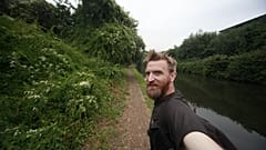 Guerrilla geographer, Daniel Raven-Ellison walking along the side of a canal 