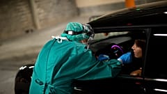 A medic takes a nose swab sample from a patient to be tested for coronavirus in a drive-in test station in Liege, Belgium.
