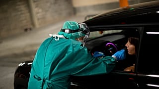 A medic takes a nose swab sample from a patient to be tested for coronavirus in a drive-in test station in Liege, Belgium.