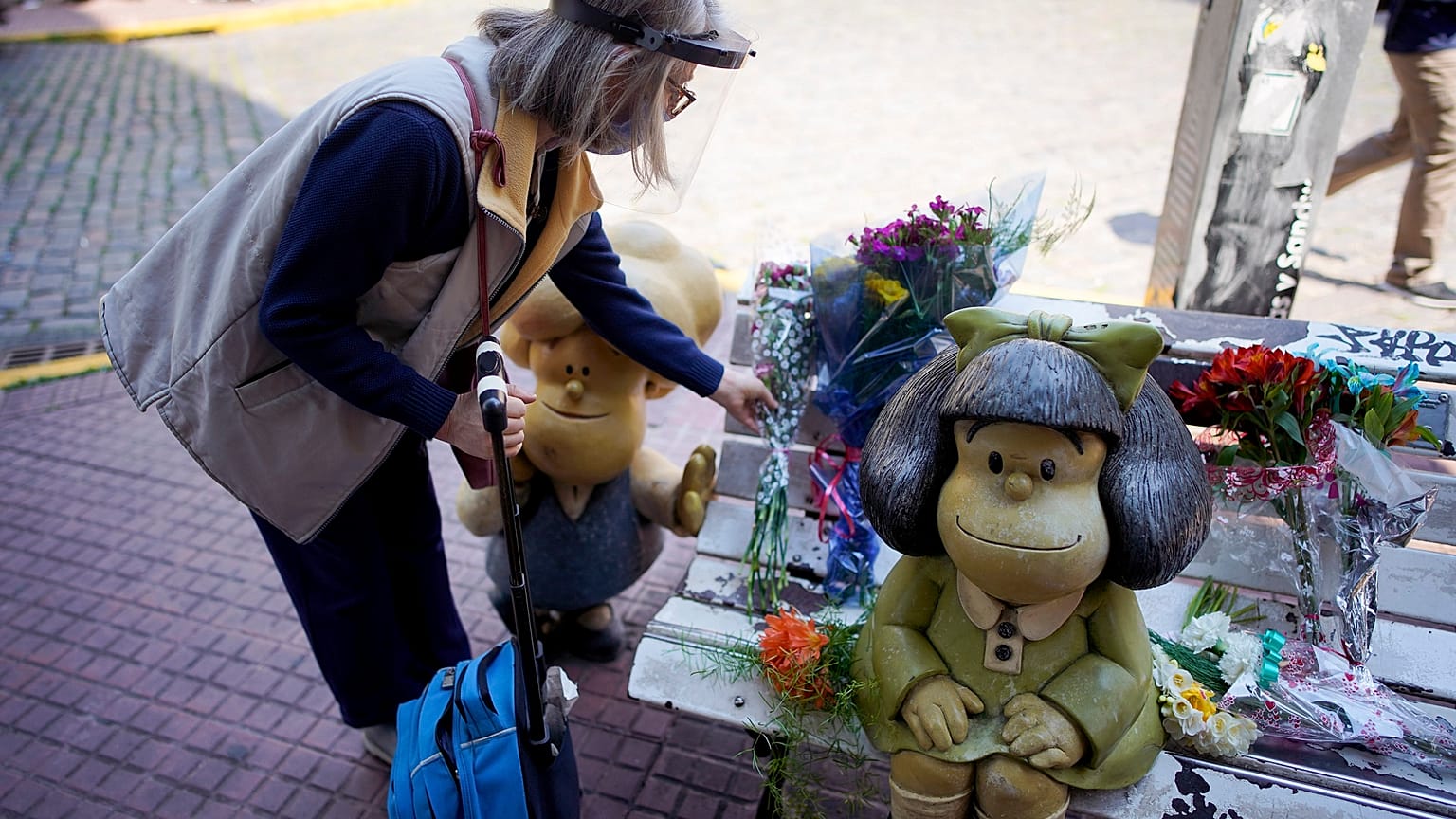 Una mujer deposita un ramo de flores en el banco de Mafalda en Buenos Aires