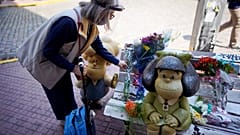 Una mujer deposita un ramo de flores en el banco de Mafalda en Buenos Aires
