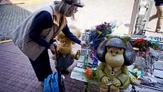 Una mujer deposita un ramo de flores en el banco de Mafalda en Buenos Aires