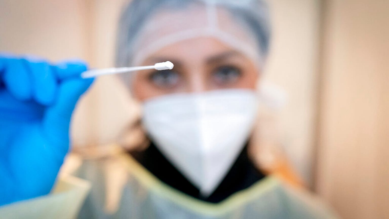 Medizinisches Personal zeigt ein Wattestäbchen für einen Rachen-Abstrich zum Corona-Test