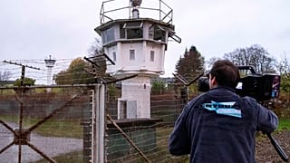 A cameraman films a control tower of the former GDR border guard forces in Moedlareuth prior to the 30th anniversary of the falling of the Berlin wall