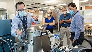 In this June 18, 2020 photo provided by NASA, astronaut Kate Rubins, center, and support personnel review the Universal Waste Management System, a low-gravity space toilet.