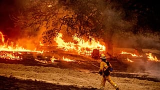 A firefighter passes flames while battling the Glass Fire in a Calistoga, Calif., vineyard Thursday, Oct. 1, 2020.