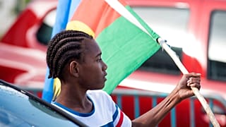 An Independence supporter holds the Kanak flag outside a voting station in the Riviere Salee district of Noumea, New Caledonia, Sunday, Oct.4, 2020