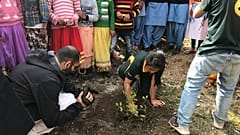 Licipriya planting a tree with a group of children.