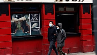 Menschen mit Gesichtsmasken vor einem Pub in Dublin, 16.03.2020