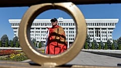 Мужчина с национальным флагом у здания правительства Киргизии