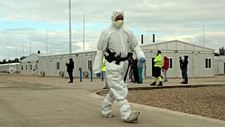 Védőruhába öltözött rendőr a tiszaújvárosi konténerlakótelepen 2020. október 8-án