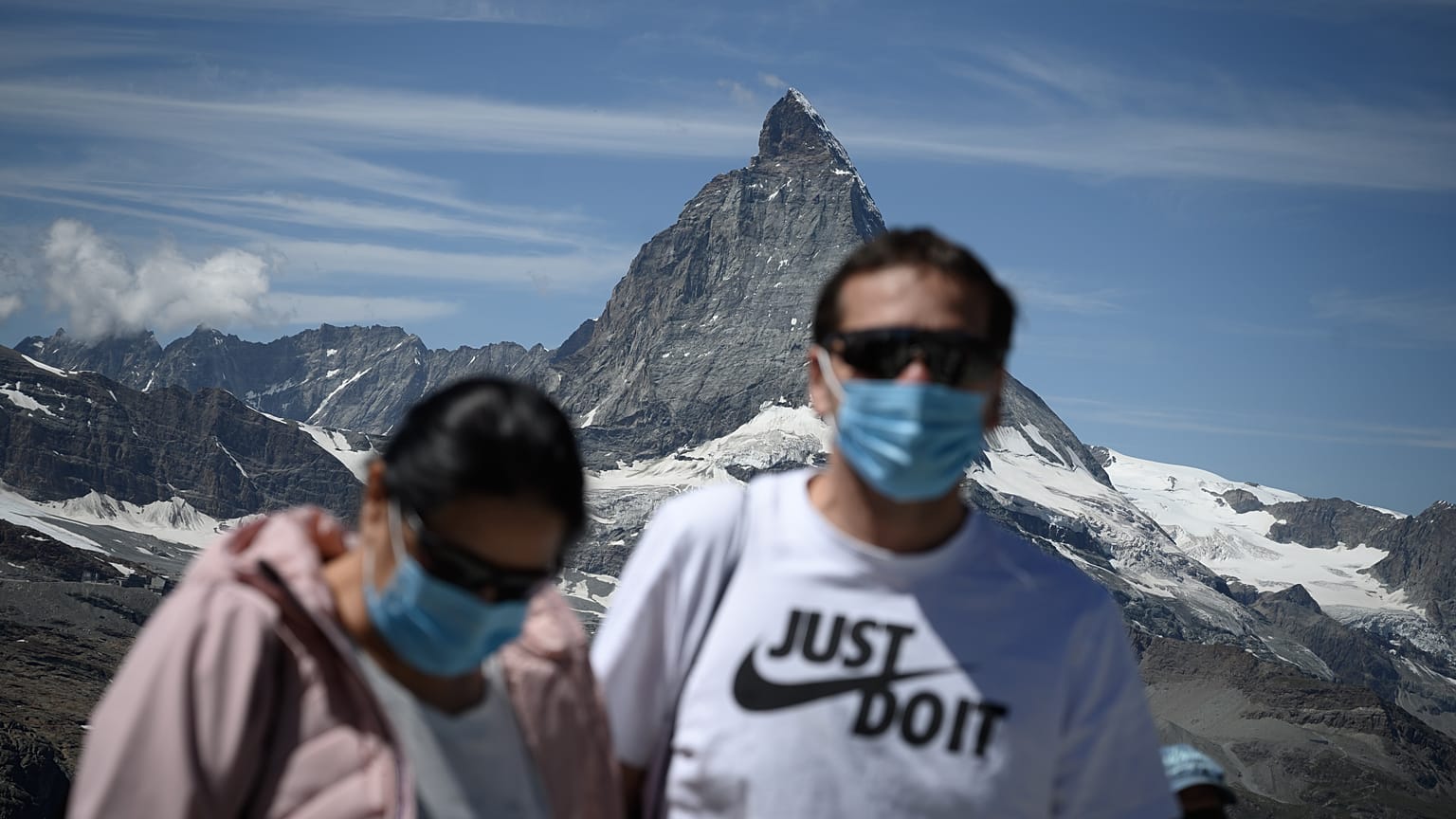 Touristen mit Mundschutz vor dem Matterhorn. 