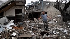 A man gestures in the yard of a house destroyed by shelling by Azerbaijan's artillery during a military conflict in Stepanakert, in Nagorno-Karabakh, Oct. 9, 2020.