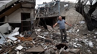 A man gestures in the yard of a house destroyed by shelling by Azerbaijan's artillery during a military conflict in Stepanakert, in Nagorno-Karabakh, Oct. 9, 2020.