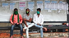 Des Indiens portant des masques de protection contre le coronavirus attendent à un arrêt de bus à Bengalore, en Inde, le dimanche 11 octobre 2020.
