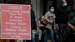 People walk past a sign that refers to COVID-19 closures in London, Friday, Oct. 9, 2020.