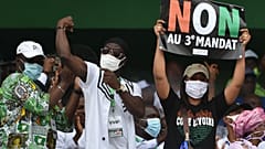 Ivorian MP Yasmina Ouegnin(R) holds a banner reading "No to third term" during a meeting against the candidacy for re-election of the incumbent president