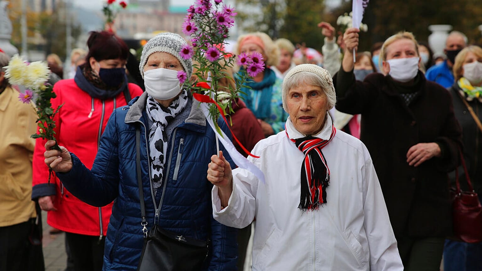 Elderly women hold flowers during an opposition rally to protest the official presidential election results in Minsk, Belarus, Monday, Oct. 12, 2020. 