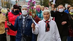Elderly women hold flowers during an opposition rally to protest the official presidential election results in Minsk, Belarus, Monday, Oct. 12, 2020. 