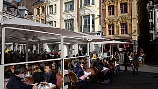 Kávézó teraszán ülő emberek a franciaországi Lille-ben