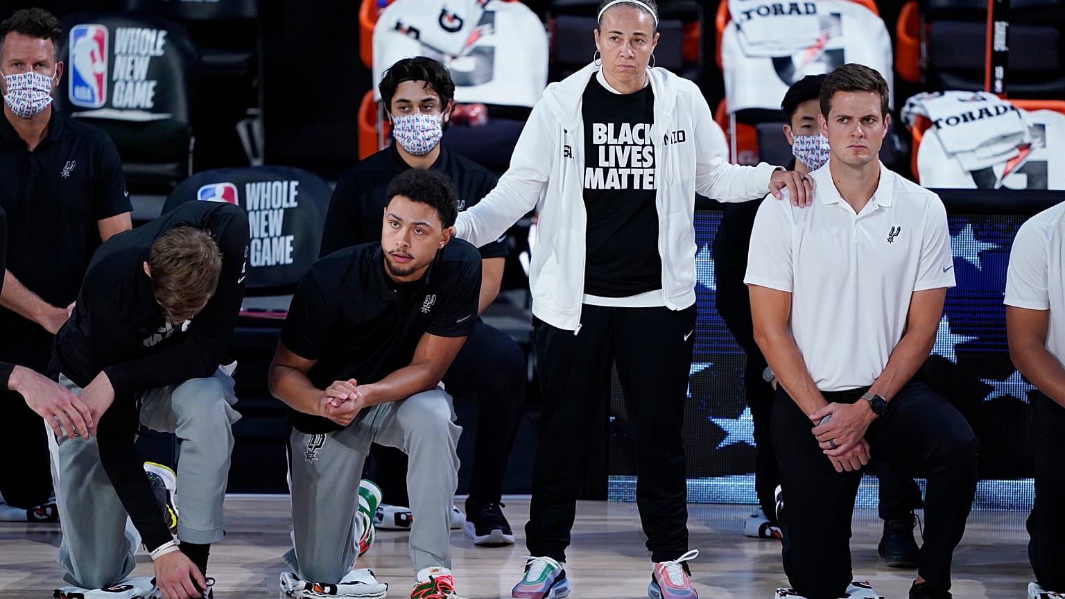 Assistenztrainerin Becky Hammon mit knieenden Spielern der San Antonio Spurs vor einem Match gegen die Memphis Grizzlies im August 2020
