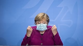 German Chancellor Angela Merkel holds her face mask as she arrives for a press conference after a meeting with the governors of the German states in Berlin, Oct. 14, 2020.