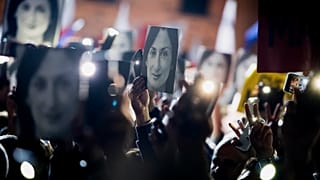 People hold pictures of slain journalist Daphne Caruana Galizia as they protest outside the office of the Maltese Prime Minister Joseph Muscat on Nov. 29, 2019.