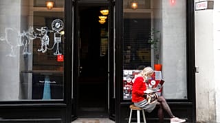 A woman sits in front of a cafe in Prague