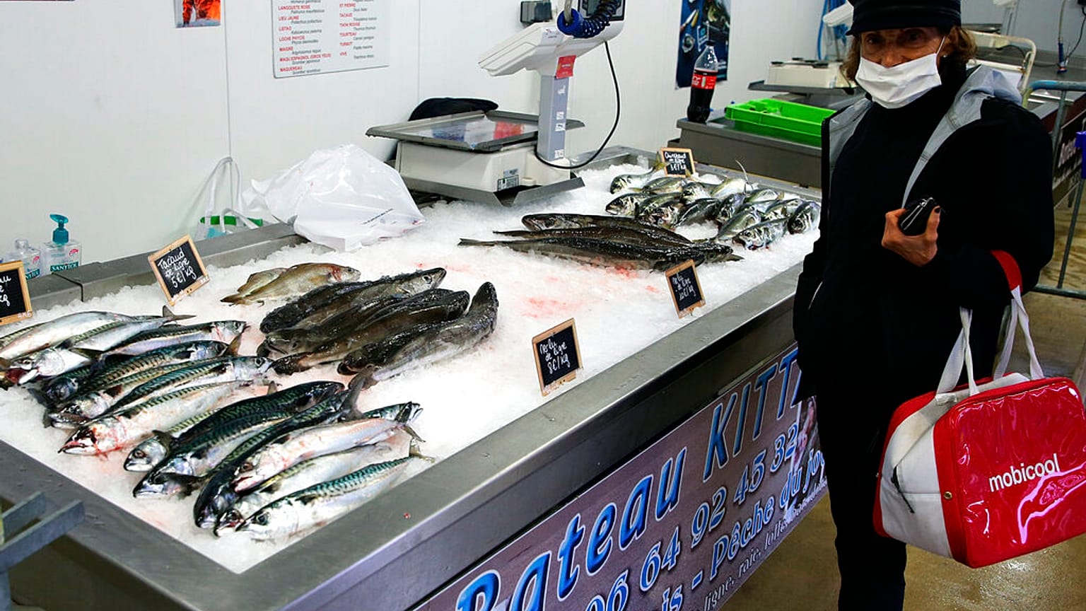file photo, a woman wearing a face mask buys fish 