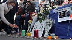 A woman lights a candle on Republique square during a demonstration in support of freedom of speech on Oct. 18, 2020 in Paris.