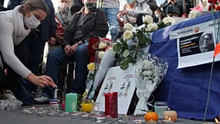 A woman lights a candle on Republique square during a demonstration in support of freedom of speech on Oct. 18, 2020 in Paris.