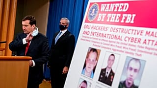 A poster showing six wanted Russian military intelligence officers is displayed as Assistant Attorney General for the National Security Division John Demers, speaks.