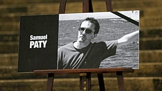 The portrait of slain teacher Samuel Paty with a black ribbon is displayed Tuesday, Oct.20, 2020 on the steps of the National Assembly in Paris.