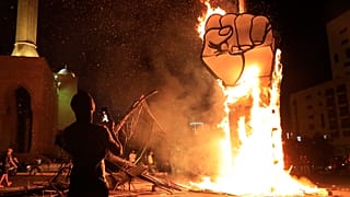 A protester takes pictures of a protest symbol that was set on fire by the supporters of former Lebanese Prime Minister Saad Hariri, Oct 21 2020