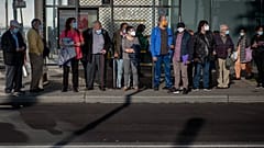 Personas esperan en una parada de bus de Barcelona