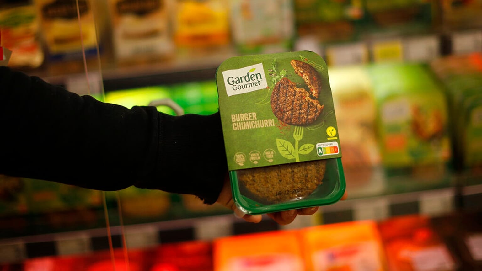 A store clerk shows a plant based burger at a supermarket chain in Brussels, Friday, Oct. 23, 2020. 