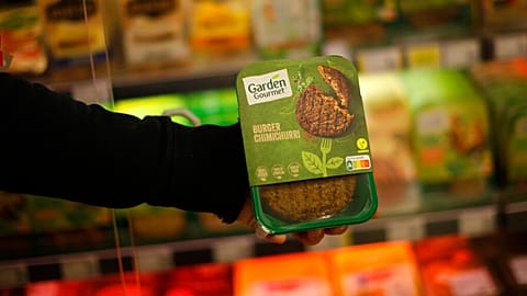 A store clerk shows a plant based burger at a supermarket chain in Brussels, Friday, Oct. 23, 2020. 