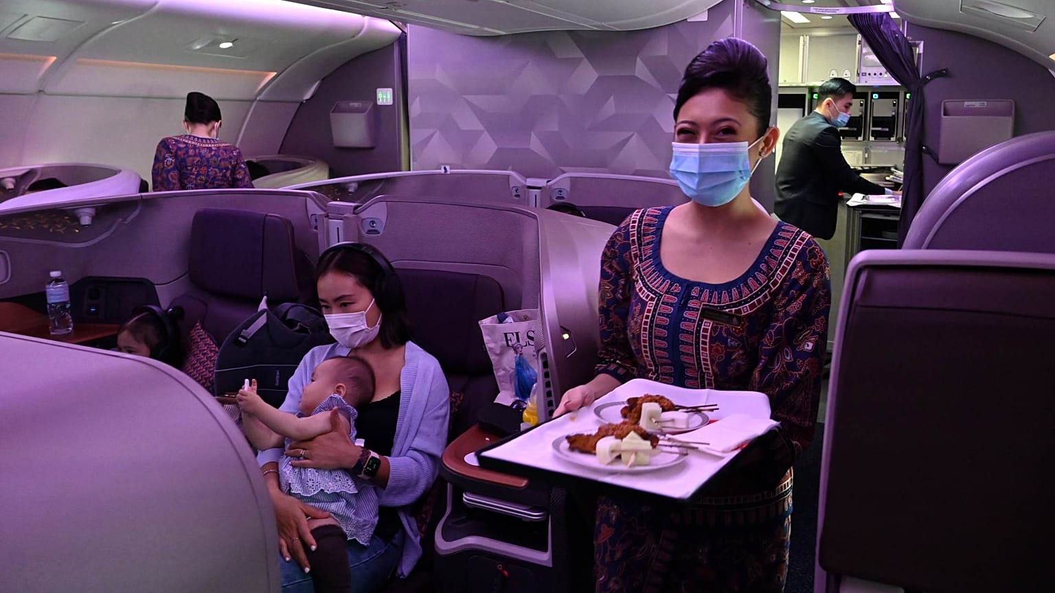 مضيفة الخطوط الجوية السنغافورية تبتسم أثناء تقديم الطعام على متن طائرة إيرباص A380 التابعة للخطوط الجوية السنغافورية، مطار شانغي الدولي في سنغافورة 24 أكتوبر 2020