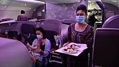 مضيفة الخطوط الجوية السنغافورية تبتسم أثناء تقديم الطعام على متن طائرة إيرباص A380 التابعة للخطوط الجوية السنغافورية، مطار شانغي الدولي في سنغافورة 24 أكتوبر 2020