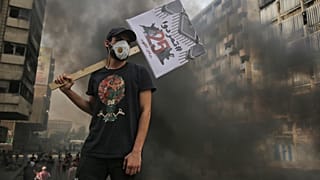 متظاهر عراقي يحمل لافتة كتب عليها بالعربية "ثمردوا" خلال مظاهرة على جسر السنك في العاصمة بغداد في 25 تشرين الأول / أكتوبر 2020.