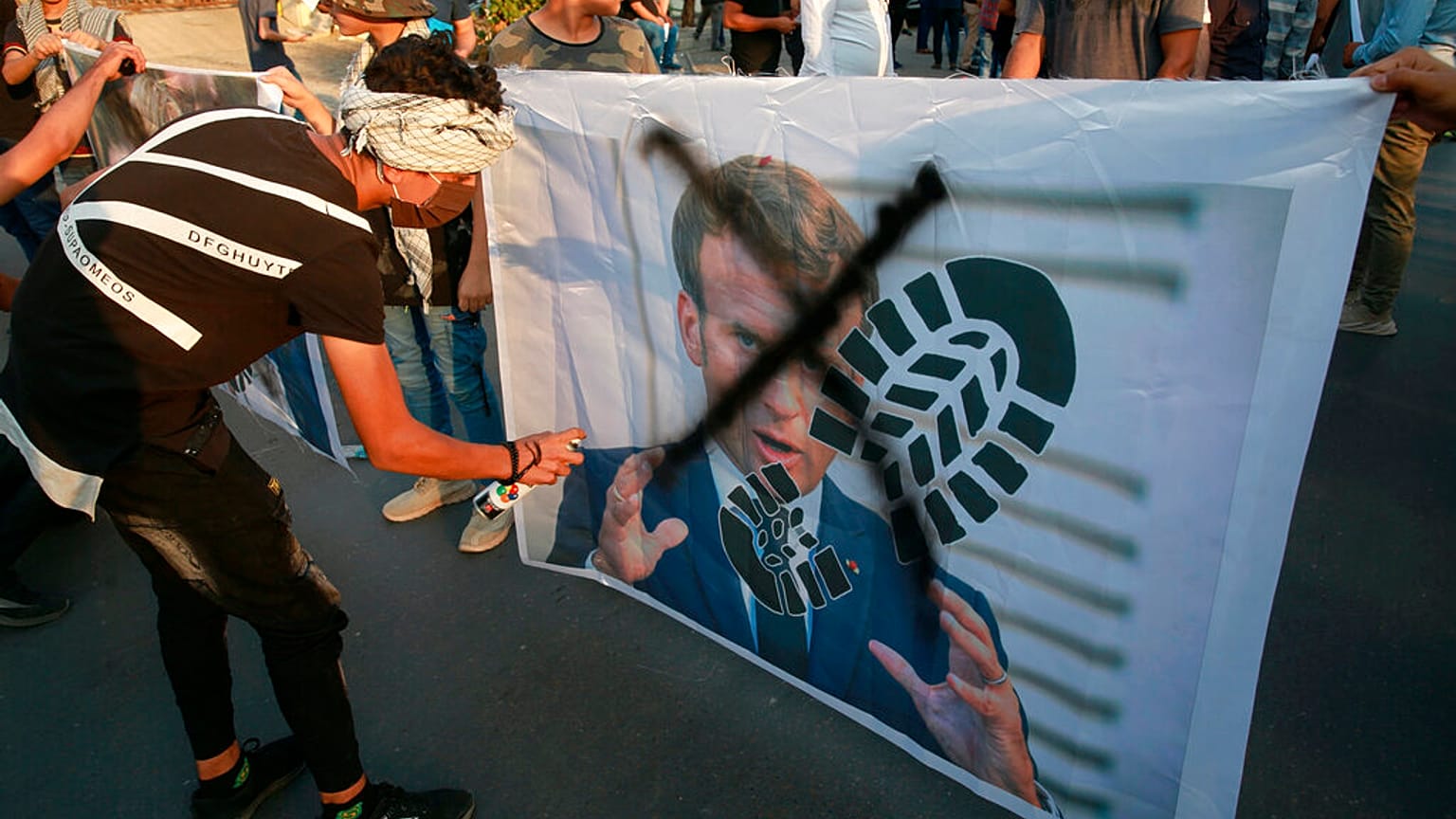 Protesters deface a photograph of French President Emmanuel Macron in Baghdad on Monday