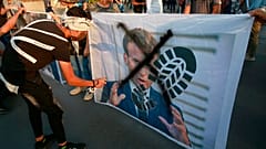 Protesters deface a photograph of French President Emmanuel Macron in Baghdad on Monday