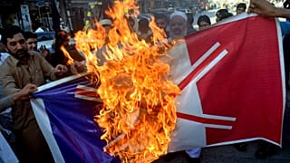 Traders burn burn a French flag during a protest against the publishing of caricatures of the Prophet Muhammad in Peshawar, Pakistan, on Monday, October 26, 2020.