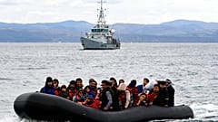 Migrants arrive with a dinghy accompanied by a Frontex vessel at the village of Skala Sikaminias