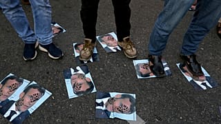 Demonstrators stand on defaced images of French President Emmanuel Macron during a protest in Karachi, Pakistan, against the publishing of caricatures of the Prophet Muhammad.
