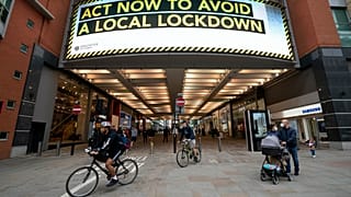 Members of the public are seen by a public information message in Manchester, England. 