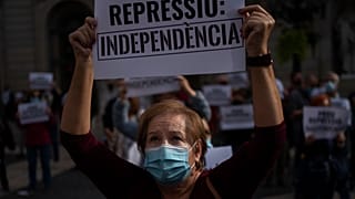 متظاهرة كتالونية ترفع لافتة كتب عليها "أوقفوا القمع" بعد اعتقال 21 شخصاً يشبته بتورطهم بهدر المال العام 