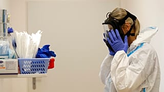 A health care worker puts on personal protective equipment (PPE) before tending to COVID-19 patients at an intensive care unit (ICU) at a hospital in Kyjov, Czech Republic.