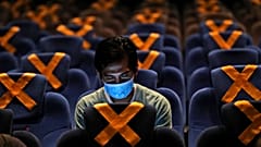 رجل يراقب هاتفه داخل قاعة سينما في العاصمة الاندونيسية جاكارتا حيث وضعت على المقاعد علامات التباعد الاجتماعي. 2020/10/23 